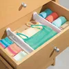 An open drawer with drawer organizers holding folded clothing. Produktbild-Vorschau