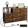 A dresser with 8 drawers and a shelf on top, featuring a vintage brown wood finish and black metal frame. A lamp and books are on the shelf. Náhľad obrázku produktu