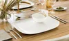 A table setting with cutlery, plates, and a vase of dried grass. Náhled obrázku produktu