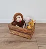Three stuffed toys are in a wooden crate on a wooden floor against a white wall. Produktbild-Vorschau