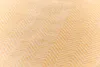 A close-up, diagonal view of a textured fabric with a herringbone pattern in gold and white. Produktbild-Vorschau