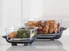 Two glass containers with food, one with chicken wings and the other with salmon and broccoli, are placed on black stands on a countertop. Anteprima dell’immagine prodotto