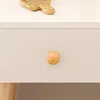 A close-up of a drawer with a wooden knob on a white surface. A shiny brass object is visible at the top. Produktbild-Vorschau