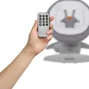 A hand holding a remote control in front of a baby swing. Produktbild-Vorschau