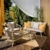 An outdoor patio set with a sofa, two chairs, and a coffee table, set against a backdrop of lush greenery and wooden walls. Náhľad obrázku produktu