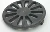 A round, cast iron grate with a spoke-like pattern and a small pin in the center, placed on a white surface. Anteprima dell’immagine prodotto