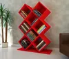 A red bookshelf filled with books, placed in a room with a plant and a chair. Produktbild-Vorschau