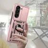 A hand holding a rose gold phone case with a ring holder and camera cover, with a blurred indoor background. Produktbild-Vorschau