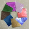A collection of colorful foil wrappers arranged in a circle on a patterned fabric background. Produktbild-Vorschau
