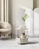 A cat is sitting in a round pet bed integrated into a side table, with a vase of greenery and a teacup on top. The scene is set in a modern, minimalist living room with soft lighting and neutral tones. Náhled obrázku produktu