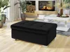 A black ottoman is placed in a living room setting with a fireplace and a coffee table. Náhľad obrázku produktu