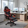 A gaming chair is shown in a home office setting with a desk, monitors, and a window. Produktbild-Vorschau