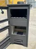 A dark gray wood-burning stove with its doors open, shown outdoors. Produktbild-Vorschau