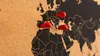 A close-up shot of a cork world map with three red pins marking locations in Europe and the Middle East. Produktbild-Vorschau
