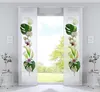Two panel curtains with floral designs are displayed in a room with a window view of greenery.