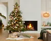 A decorated Christmas tree stands next to a fireplace with a fire burning. Presents are at the base of the tree. Voir les images du produit