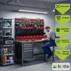 A man working in a well-organized garage or workshop with a tool wall and workbench. Anteprima dell’immagine prodotto