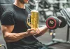 A person in a gym holding a beer and a dumbbell. Produktbild-Vorschau