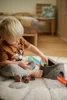 A young child is playing with a toy car track on a rug. Produktbild-Vorschau