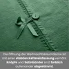 Close-up of a green Christmas tree skirt showing stitching, a button, and a ribbon bow. Náhľad obrázku produktu