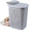 A laundry basket with a lid and rolled towels next to it, on a white background. Produktbild-Vorschau