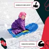 A child is sitting on a blue sled in the snow. Voir les images du produit