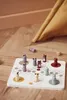A board game with wooden animal pieces is set up on a wooden floor, with a yellow tent in the background. Produktbild-Vorschau