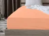 A close-up view of a peach-colored fitted sheet on a bed. Produktbild-Vorschau