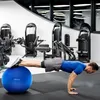 A man is doing a plank exercise with his feet on a blue exercise ball in a gym. Voir les images du produit