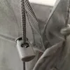 A close-up of a gray drawstring with a plastic toggle on a gray fabric. Produktbild-Vorschau