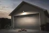 A garage door with a bicycle and skateboards in front of it, illuminated by a floodlight. Voir les images du produit