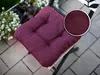 A close-up of a purple seat cushion on a chair outdoors, with a planter of white flowers in the background. Produktbild-Vorschau