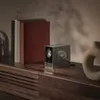 A projector sits on a wooden shelf next to books and a vase. Produktbild-Vorschau