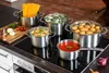 A collection of stainless steel pots and pans filled with various ingredients, arranged on a stovetop. Produktbild-Vorschau
