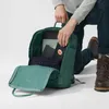 A person is kneeling and placing items into a green backpack. Náhľad obrázku produktu