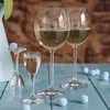 Three glasses of white wine are arranged on a blue wooden surface, with small blue decorative balls scattered around. Náhľad obrázku produktu