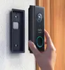 A hand is holding a black Eufy video doorbell next to its mounting bracket, which is attached to a white wall. Voir les images du produit