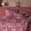 A close-up view of a bed with red paisley patterned bedding. Produktbild-Vorschau