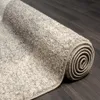 A rolled-up rug on a dark wooden floor. Produktbild-Vorschau