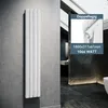 A modern bathroom with a vertical panel radiator mounted on a gray concrete wall. The radiator is white and sleek. An inset image shows a close-up of the radiator's connection and text details. Anteprima dell’immagine prodotto