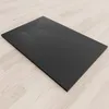 A black shower tray with a textured surface is placed on a light wooden floor. Produktbild-Vorschau