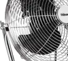 A close-up view of a silver floor fan with a chrome grille. Podgląd zdjęcia produktu