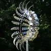 A kinetic wind sculpture made of stainless steel, standing outdoors with trees in the background. Anteprima dell’immagine prodotto
