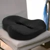 A black orthopedic seat cushion is placed on a white chair. Podgląd zdjęcia produktu
