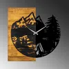 A wooden clock with a mountain and forest scene depicted on it. Voir les images du produit