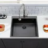 A black kitchen sink with a faucet is shown in a modern kitchen setting. Produktbild-Vorschau