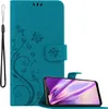 A teal flip phone case with a floral and butterfly design is shown open, with a smartphone inside. A black wrist strap is attached to the case. Náhled obrázku produktu