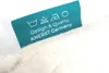 A close-up of a fabric care label attached to a product. Produktbild-Vorschau