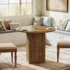 A dining set with a round table and chairs in a bright room with a large window. Produktbild-Vorschau