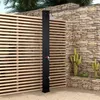 An outdoor shower in a garden setting with a wooden slatted fence and a stone wall. Produktbild-Vorschau